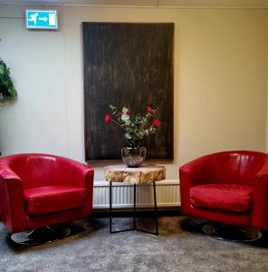 two red chairs and a table with a vase of flowers at Vandrarhemmet Eken in Eksjö