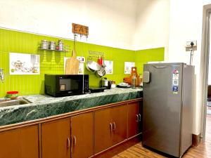 a kitchen with green walls and a stainless steel refrigerator at AnandMai Ghar - A Homestay in Gwalior in Gwalior