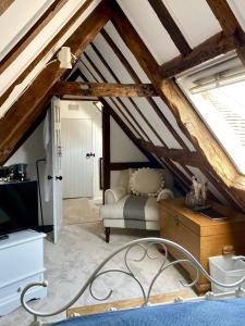 Zimmer im Dachgeschoss mit einem Bett und einem Fenster in der Unterkunft Chestnut Tree Cottage, 7 High Street in Ardingly