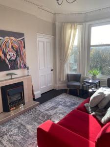a living room with a red couch and a fireplace at Beautiful traditional flat in the center of Largs. in Largs