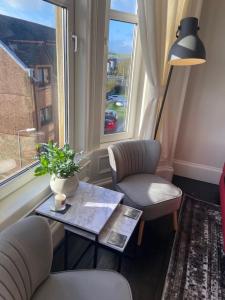 a living room with a table and chairs and a window at Beautiful traditional flat in the center of Largs. in Largs