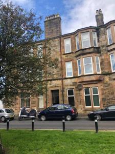 a large brick building with cars parked in front of it at Beautiful traditional flat in the center of Largs. in Largs