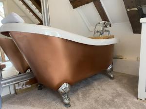 a bath tub with a sink in a room at Chestnut Tree Cottage, 7 High Street in Ardingly
