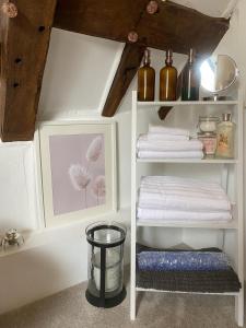 una habitación con un estante con toallas y una foto en Chestnut Tree Cottage, 7 High Street en Ardingly