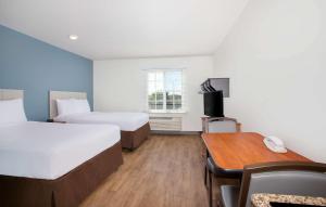 a hotel room with two beds and a desk and a table at Extended Stay America Select Suites - Fort Myers - Northeast in Fort Myers