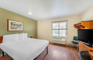 a bedroom with a white bed and a flat screen tv at Extended Stay America Select Suites - Tuscaloosa in Tuscaloosa