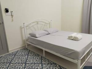 un letto bianco con asciugamani in una stanza di Homestay Gunung Reng, Jeli a Kampong Jeli Kerawat