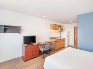 a small room with a bed and a desk with a television at Extended Stay America Select Suites - Bentonville in Bentonville