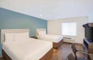 a hotel room with two beds and a television at Extended Stay America Select Suites - Bentonville in Bentonville