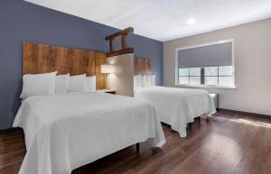 Duas camas num quarto com paredes azuis e uma janela em Extended Stay America Premier Suites - Charlotte - Pineville - Pineville Matthews Rd. em Charlotte