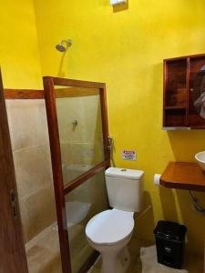 uma casa de banho amarela com um WC e um chuveiro em Casa amarela flecheiras em Trairi