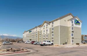 un grand immeuble avec des voitures garées dans un parking dans l'établissement Extended Stay America Select Suites - Colorado Springs - Airport, à Colorado Springs