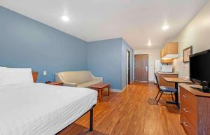 - une chambre avec un lit et un bureau avec une télévision dans l'établissement Extended Stay America Select Suites - Colorado Springs - Airport, à Colorado Springs