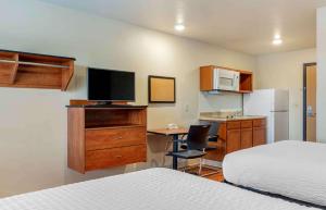 Extended Stay America Select Suites - Atlanta - Chamblee في أتلانتا: غرفة فندقية بسرير ومكتب مع تلفزيون