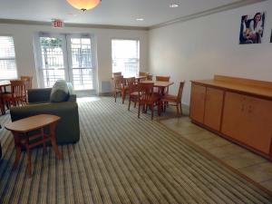 een wachtkamer met een bank en tafels en stoelen bij Extended Stay America Suites - Greensboro - Airport in Greensboro