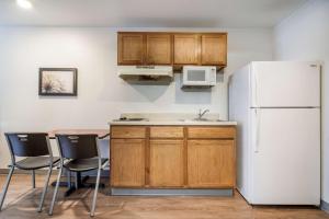 eine Küche mit einem weißen Kühlschrank sowie einem Tisch und Stühlen in der Unterkunft Extended Stay America Select Suites - Fayetteville in Fayetteville