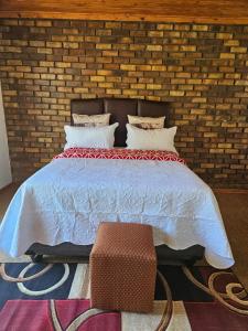 a bedroom with a bed with a brick wall at Good Life Guest house in Orkney +27731671754 in Orkney