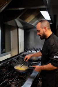 a man stirring a pot on a stove in a kitchen at Hotel Il Ceppo in Agropoli