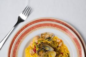 a plate of food with shrimp and pasta with a fork at Hotel Il Ceppo in Agropoli