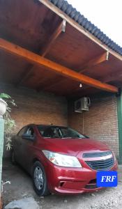 un coche rojo estacionado frente a un garaje en F R F departamentos turisticos en San Rafael