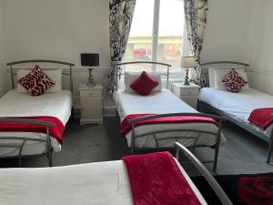 a room with two beds with red pillows on them at The Angerstein Hotel in London