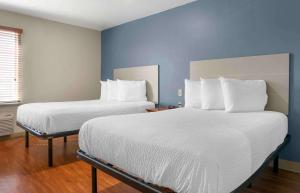 Extended Stay America Select Suites - Kalamazoo - West في كالامازو: سريرين في غرفة بجدران زرقاء
