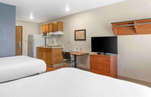 Extended Stay America Select Suites - Kalamazoo - West في كالامازو: غرفة فندقية بسريرين ومطبخ مع تلفزيون