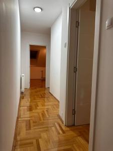 Un pasillo vacío con piso de madera y un armario. en Riverside apartment with private parking, en Niš
