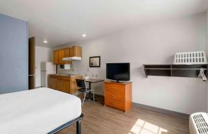 Extended Stay America Select Suites - Lakeland في ليكلاند: غرفة نوم بسرير ومكتب مع تلفزيون