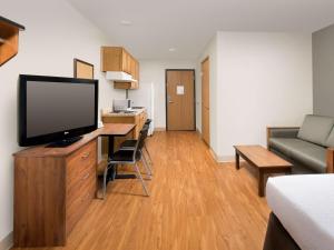 ein Wohnzimmer mit einem TV und einem Schreibtisch mit einem Sofa in der Unterkunft Extended Stay America Select Suites - Las Cruces in Las Cruces