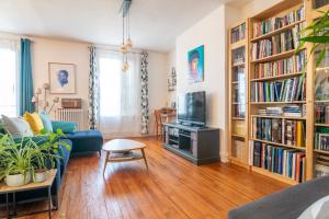 a living room with a couch and a tv and bookcases at Escapade Culturelle Havraise in Le Havre