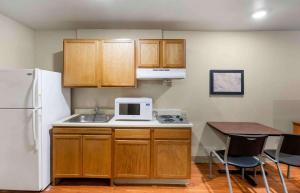 a kitchen with wooden cabinets and a white microwave at Extended Stay America Select Suites - Lubbock - South in Lubbock