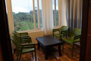 a room with green chairs and a table and a window at LAZY RETREAT in Vagamon