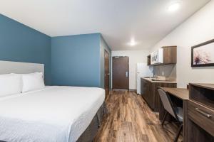 Mendota HeightsにあるExtended Stay America Suites - Minneapolis - Airport - Mendota Heightsのベッド、デスク、キッチンが備わるホテルルームです。