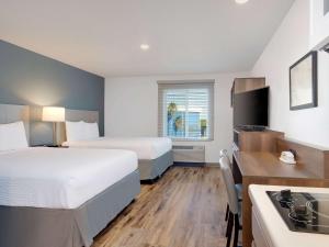 Extended Stay America Select Suites - Melbourne - West Melbourne في ملبورن: غرفة فندقية بسريرين ومطبخ
