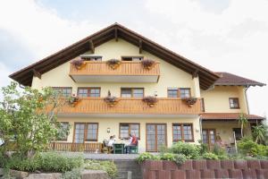 ein Haus mit einem Balkon und Menschen am Tisch in der Unterkunft Landhaus Weber in Bad König