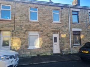 a brick building with a white door and windows at Amazing 2 Bedrooms House in Bridgend