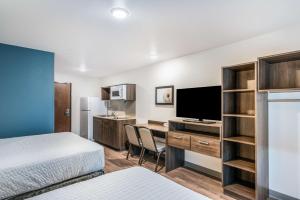 オーランドにあるExtended Stay America Select Suites - Orlando - Kissimmeeのベッド、デスク、コンピュータが備わるホテルルームです。