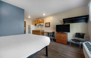 Extended Stay America Select Suites - Ogden في أوغدن: غرفة بسرير ومطبخ مع تلفزيون