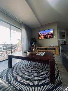 sala de estar con sofá y TV de pantalla plana en Rosebud 4 Beacon Point, en Mossel Bay
