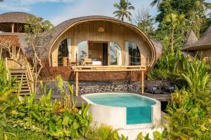 een ovaal huis met een zwembad ervoor bij Jungleight Bali in Tegalalang