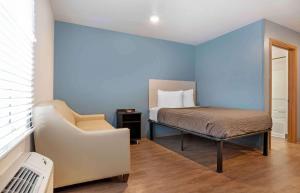 a bedroom with a bed and a chair in it at Extended Stay America Select Suites - Pensacola - Northeast in Pensacola