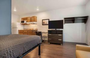 a bedroom with a bed and a desk with a television at Extended Stay America Select Suites - Pensacola - Northeast in Pensacola +17 photos