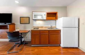a kitchen with a white refrigerator and a table and a desk at Extended Stay America Select Suites - Oklahoma City - West in Oklahoma City