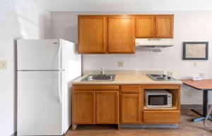 a kitchen with a white refrigerator and a sink at Extended Stay America Select Suites - Orlando - East in Orlando