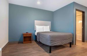 a blue bedroom with a bed and a wooden floor at Extended Stay America Select Suites - Pensacola - Northwest in Pensacola
