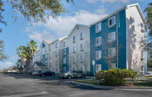 um grande edifício de apartamentos com carros estacionados num parque de estacionamento em Extended Stay America Select Suites - Orlando - South em Orlando
