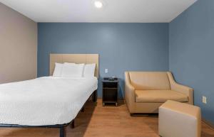 een slaapkamer met een groot bed en een stoel bij Extended Stay America Select Suites - Orlando - South in Orlando