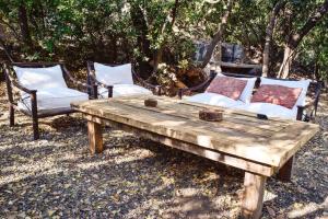 een houten tafel met 2 stoelen en een bank bij Iluminada casa de piedra entre bosque y río in Lo Barnechea