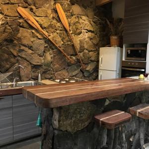 - une cuisine avec une table en bois et un mur en pierre dans l'établissement Iluminada casa de piedra entre bosque y río, à Lo Barnechea